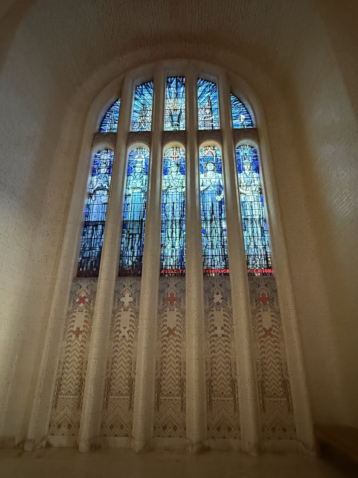 Interior of the Hall of Memory with stained-glass windows, the Tomb of the Unknown Australian Soldier and a distant visitor.